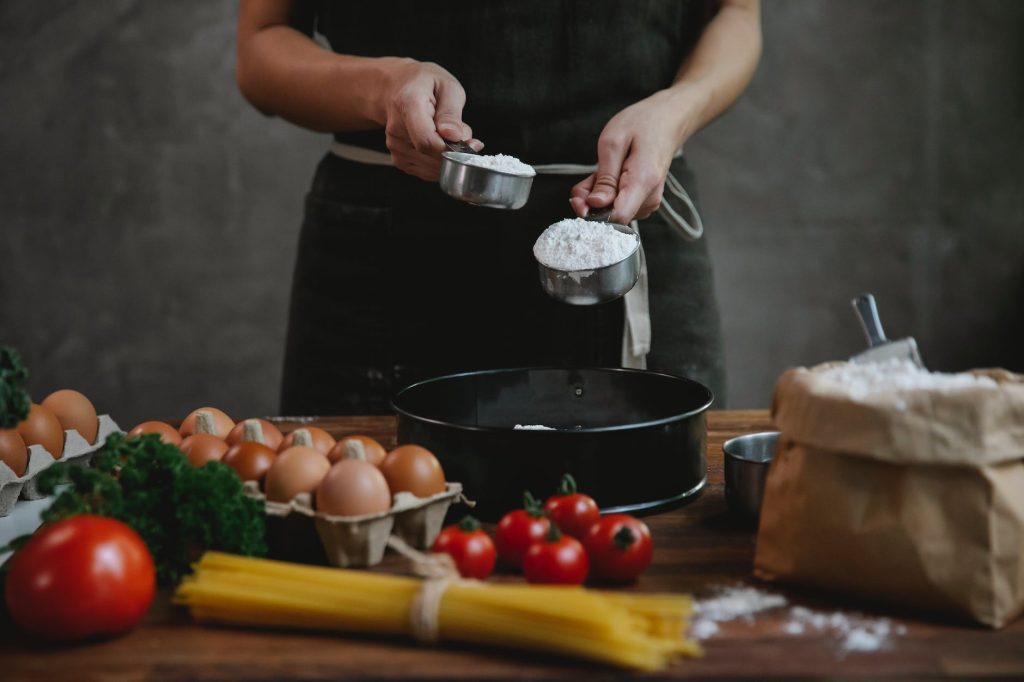 anonymous chef cooking pasta on table near ingredients